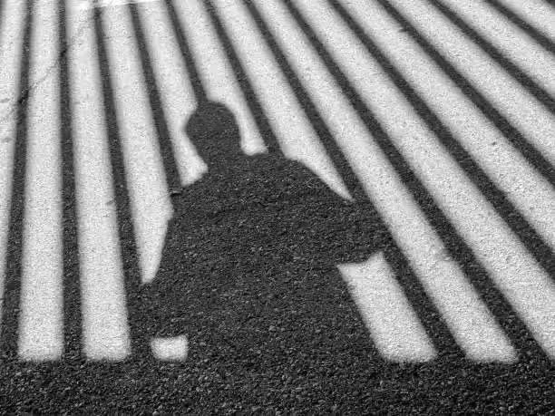 The shadow of a man behind bars