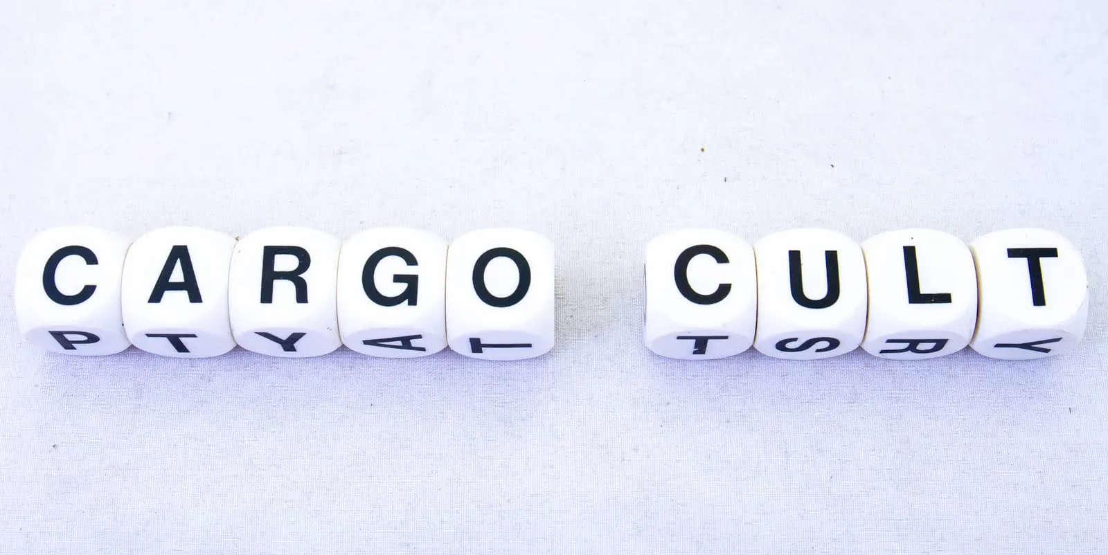 Dices with letters on each of their side. The words "cargo cult" is created with the dices